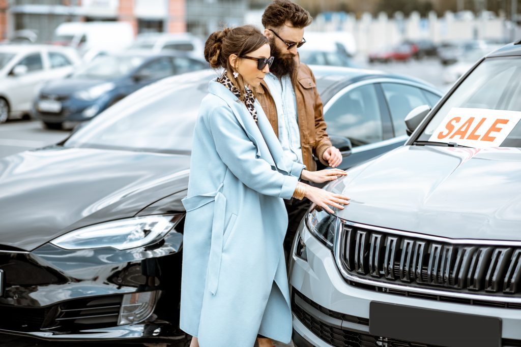 young couple inspecting a used car for sale