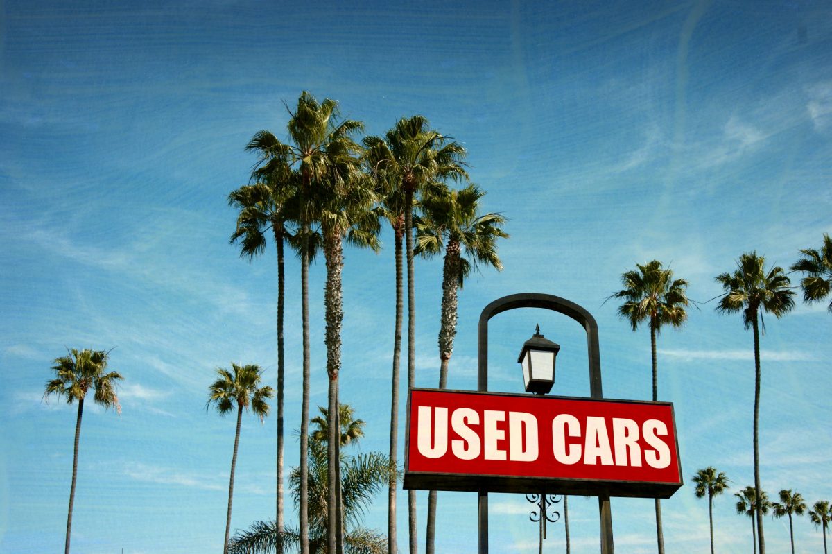 used cars sign with palm trees and sky